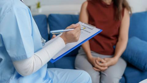 Female doctor taking notes while interviewing patient