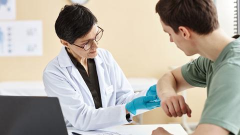 Portrait of mature female doctor inspecting patient with skin rash during consultation in dermatology clinic