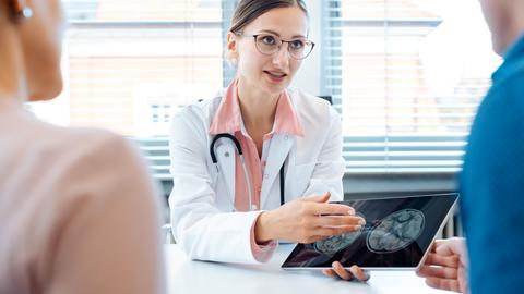 Doctor showing patients x-ray pictures on her tablet computer