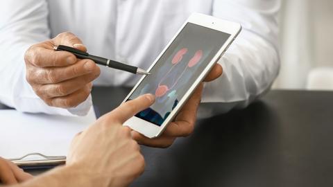 Urologist with table computer explaining patient his diagnosis, closeup