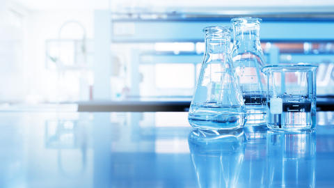 Water in beaker and flask glass in chemistry blue science laboratory background