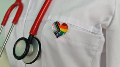 Silhouette of doctor in white coat with stethoscope and LGBT badge on pocket