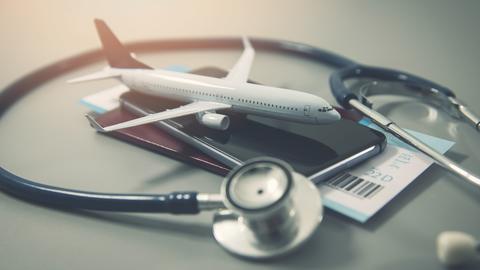 A model airplane on a smartphone, surrounded by a stethoscope and a partially visible boarding pass, symbolizing travel and healthcare.