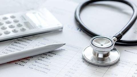 Healthcare costs with billing statement, stethoscope and calculator on stone table