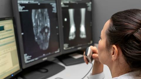 radiology doctor examines foot, ankle x-ray, mr image and reports with microphone looking computer screen