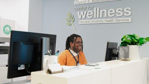 The front desk of the Center for Wellness and Health Promotion, with a young man greeting patients