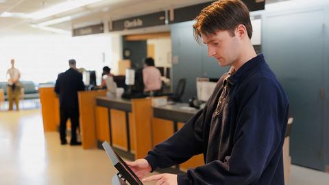 College student checking in for him appointment using the kiosk