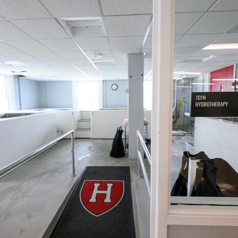 Interior view of a hydrotherapy room with white tubs, a red and white "H" emblem, and a sign reading "101N HYDROTHERAPY."