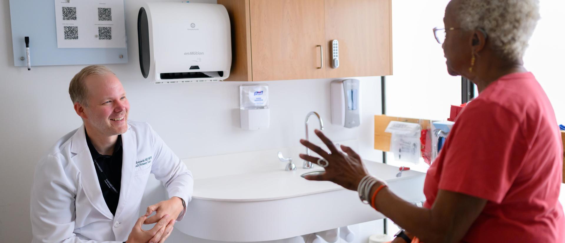 A physician and his patient happily having a discussion while in an exam room