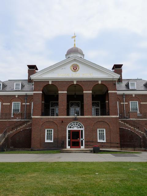 Dillon Fieldhous, a brick building with a dome and central entrance, featuring large windows, a staircase, and flower pots on the lawn.